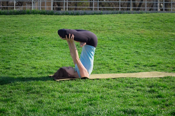 Młody piękny pasuje Asanami joga kobieta doeing na zielonej trawie z matę do jogi — Zdjęcie stockowe