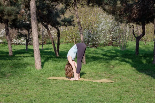 O tânără care face exerciții de yoga în parcul orașului de vară . — Fotografie, imagine de stoc