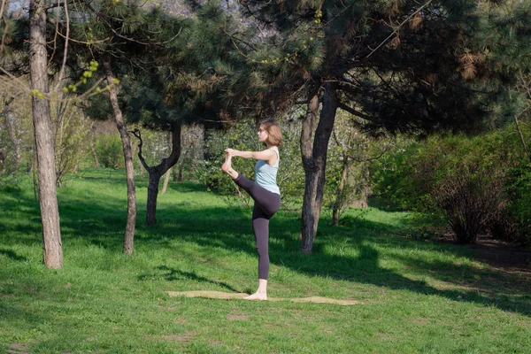 Młoda kobieta robi ćwiczenia jogi w parku miejskim lato. — Zdjęcie stockowe