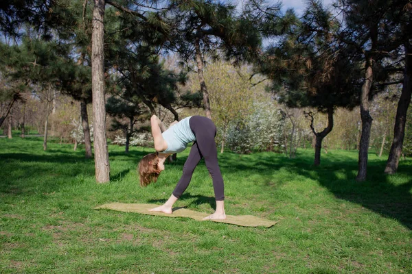 Młoda kobieta robi ćwiczenia jogi w parku miejskim lato. — Zdjęcie stockowe