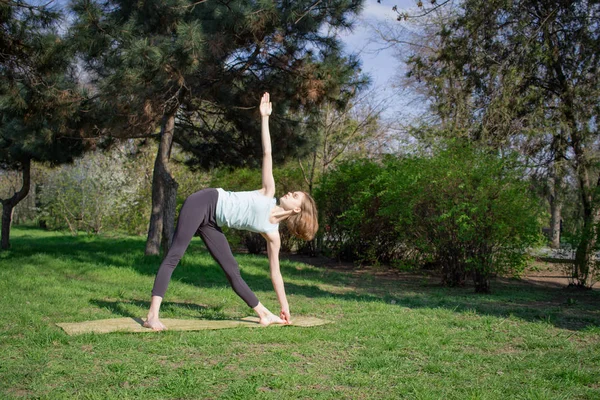 O tânără care face exerciții de yoga în parcul orașului de vară . — Fotografie, imagine de stoc