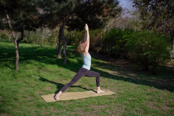 Genç güzel kadın doeing yoga asans pines Park yoga mat ile yerleştirmek — Stok fotoğraf