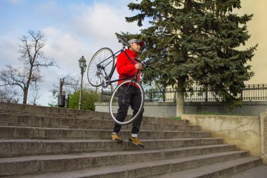 Genç hipster siyah fixedgear motor, eski Avrupa şehri arka planı ile merdivenlerden aşağı yürüyüş