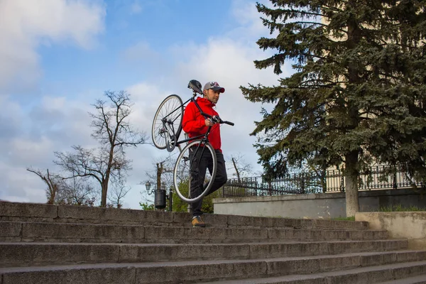 Junger Hipster geht mit schwarzem Fahrrad die Treppe hinunter, alter europäischer Stadthintergrund — Stockfoto