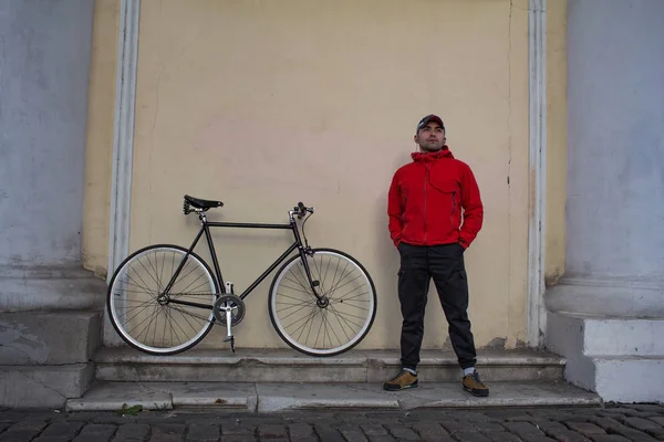 Mladí bokovky fixedgear rider pózuje u zdi starého města s černým kol — Stock fotografie