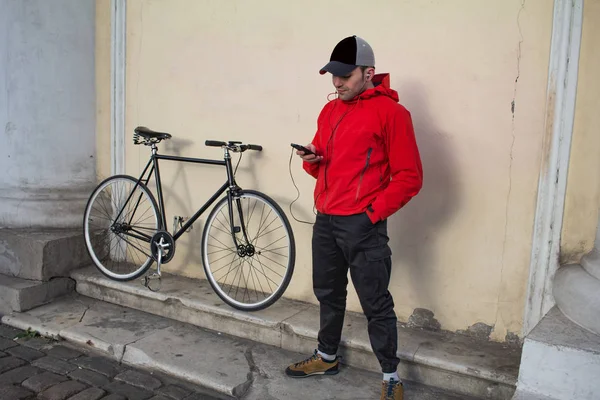 Mladí kolo rider stát poblíž zdi s mobil — Stock fotografie