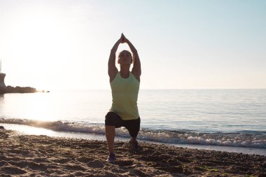 kum, sabah deniz ya da okyanus zemin üzerine karışık fitness yarış Asyalı kadın yoga poz sabah sahilde güzel kadın pratik fitness egzersiz