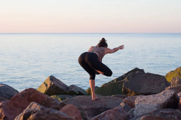 Fitness misto razza asiatico donna in posa yoga sulla spiaggia del mattino, bella forma donna pratica fitness exrxise pietre, mattina mare o oceano sfondo — Foto Stock