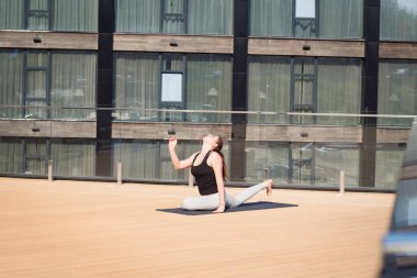 yoga mat ahşap zemin standlı otel çatısında germe yoga egzersiz yaparak spor kadın