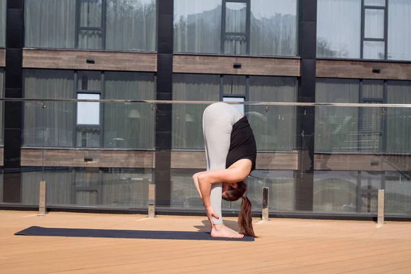 Kobieta Sport robi rozciągające ćwiczenia jogi na dachu hotelu z drewniany stojak na matę do jogi — Zdjęcie stockowe