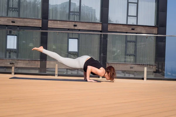 Αθλητισμός γυναίκα κάνει τεντώνοντας άσκηση γιόγκα στην οροφή του ξενοδοχείου με ξύλινο πάτωμα στάση στο χαλάκι γιόγκα — Φωτογραφία Αρχείου