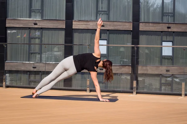 Mujer del deporte haciendo ejercicio de yoga estiramiento en el techo del hotel con soporte de piso de madera en la estera de yoga — Foto de Stock