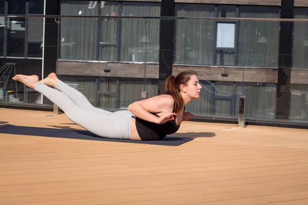 Kobieta Sport robi rozciągające ćwiczenia jogi na dachu hotelu z drewniany stojak na matę do jogi — Zdjęcie stockowe