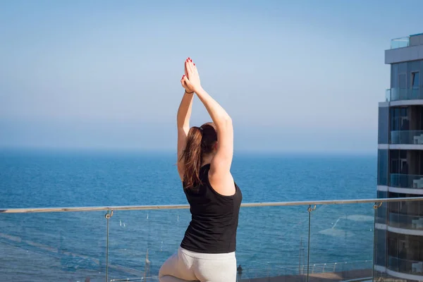 Mujer del deporte haciendo ejercicio de yoga estiramiento en el techo del hotel con soporte de piso de madera en la estera de yoga —  Fotos de Stock