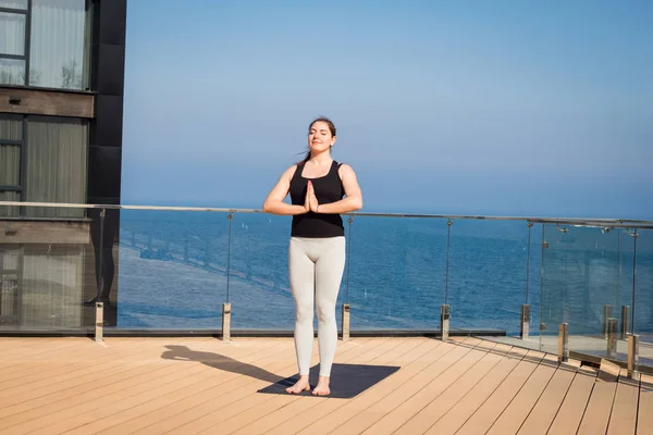 Femeie sport face exerciții de yoga stretching pe acoperișul hotelului cu suport de podea din lemn pe covor de yoga — Fotografie, imagine de stoc