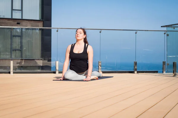 Donna sportiva che fa stretching esercizio di yoga sul tetto dell'hotel con supporto pavimento in legno su tappetino yoga — Foto Stock