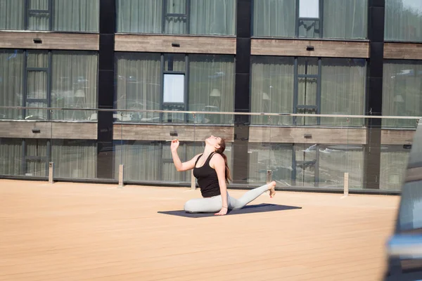 스포츠 여자 요가 매트에 나무 바닥 스탠드 호텔 지붕에 스트레칭 요가 운동을 하 고 — 스톡 사진