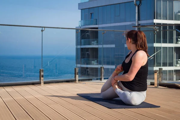 Mujer del deporte haciendo ejercicio de yoga estiramiento en el techo del hotel con soporte de piso de madera en la estera de yoga — Foto de Stock