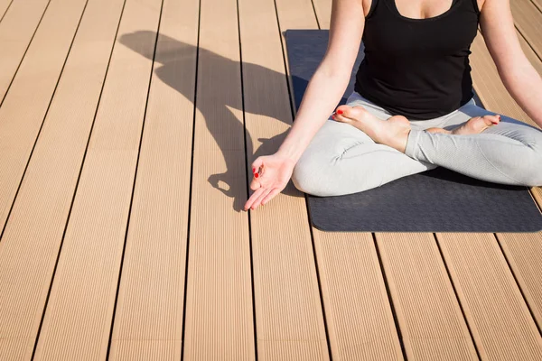 Imagen de cerca de una chica de yoga meditando en un piso de madera — Foto de Stock
