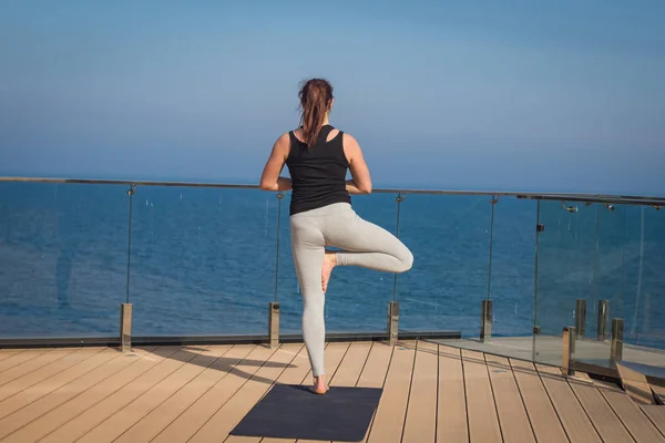 Yoga mat ahşap zemin standlı otel çatısında germe yoga egzersiz yaparak spor kadın — Stok fotoğraf