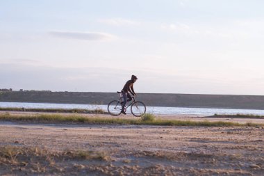 Tek başına sürücü üzerinde sabit dişli Nehri, hipster turist Bisiklet binici resimler yakınında çölde at binme yol bisikleti.