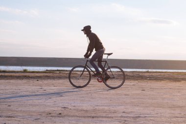 Tek başına sürücü üzerinde sabit dişli Nehri, hipster turist Bisiklet binici resimler yakınında çölde at binme yol bisikleti.