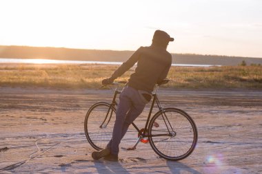 Tek başına sürücü üzerinde sabit dişli Nehri, hipster turist Bisiklet binici resimler yakınında çölde at binme yol bisikleti.