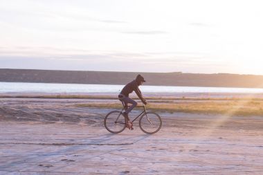 Tek başına sürücü üzerinde sabit dişli Nehri, hipster turist Bisiklet binici resimler yakınında çölde at binme yol bisikleti.