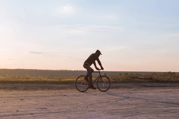 Alone rider on fixed gear road bike riding in the desert near river, hipster tourist bicycle rider pictures. — Stock Photo, Image