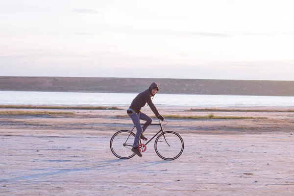 Jinete solo en bicicleta de carretera de engranaje fijo montar en el desierto cerca del río, hipster turista ciclista imágenes . — Foto de Stock