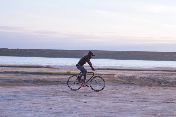 Jinete solo en bicicleta de carretera de engranaje fijo montar en el desierto cerca del río, hipster turista ciclista imágenes . — Foto de Stock