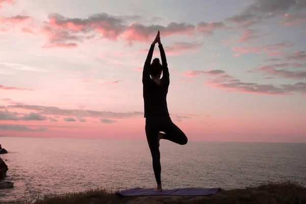 Kadın egzersiz güzel dağlar peyzaj açık germe yoga yaparken uygun. Deniz ve gündoğumu veya günbatımı arka plan eğitim asans taşla kadın. Yoga pozlar kadın silüeti