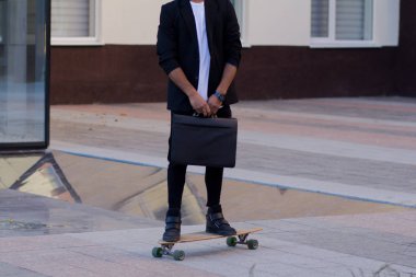 Genç, hızlı ve mobil Yöneticisi kavramı. Siyah elbiseli kaykay üzerinde komik buisinessman.