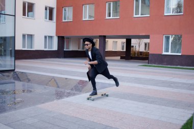 Genç, hızlı ve mobil Yöneticisi kavramı. Siyah elbiseli kaykay üzerinde komik buisinessman.