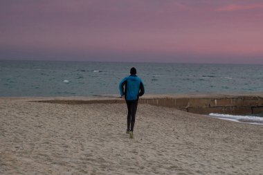 Sabah, gündoğumu karşı deniz ya da okyanus plajda genç erkek atlet. 