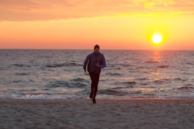 Sabah, gündoğumu karşı deniz ya da okyanus plajda genç erkek atlet. 