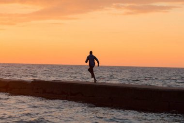 Sabah, gündoğumu karşı deniz ya da okyanus plajda genç erkek atlet. 