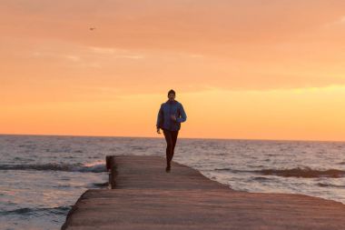 Sabah, gündoğumu karşı deniz ya da okyanus plajda genç erkek atlet. 