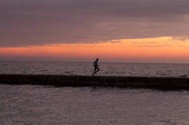 Sabah, gündoğumu karşı deniz ya da okyanus plajda genç erkek atlet. 