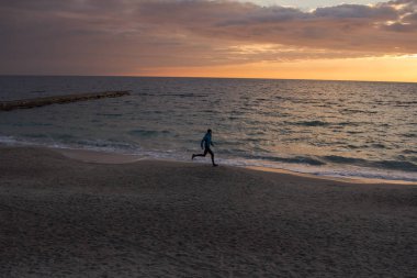 Sabah, gündoğumu karşı deniz ya da okyanus plajda genç erkek atlet. 
