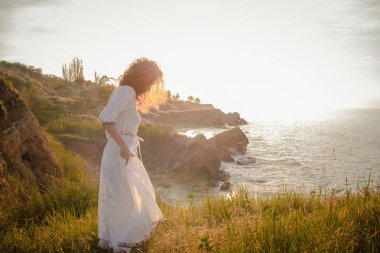 güzel beyaz elbiseli sabah sahilde yürüyen genç kadın. Uygun erkek eğleniyor turing sırasında güneşin doğuşunu.