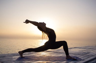 Sisin içinde gündoğumu sırasında yoga fitness yapıyor ince siyah giymek güzel genç kadın.