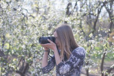 Beyaz arka plan üzerinde çiçekler Bahar park, fotoğraf makinesi ile poz genç kadın