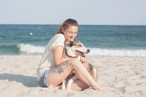 Genç kadın ile köpek yaz güneşli gün sahilde
