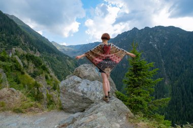 Güzel dağlarda panço giymiş genç bir bayan gezgin. 