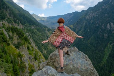 Güzel dağlarda panço giymiş genç bir bayan gezgin. 