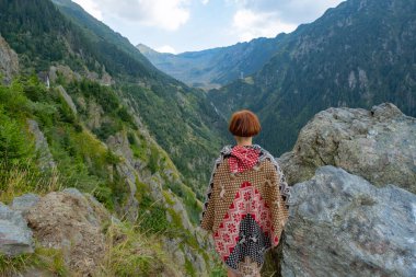 Güzel dağlarda panço giymiş genç bir bayan gezgin. 