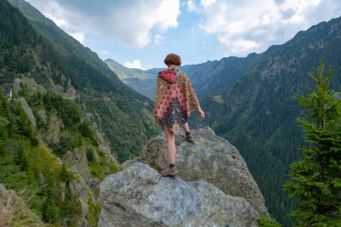 Güzel dağlarda panço giymiş genç bir bayan gezgin. 