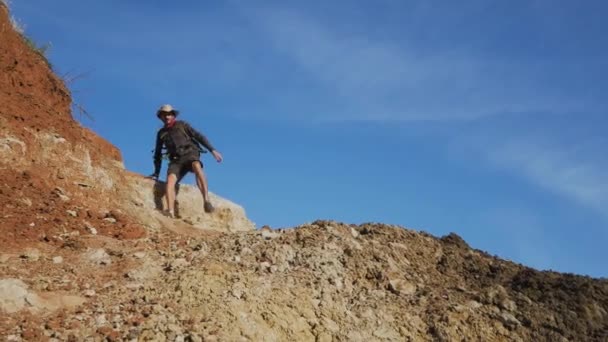 Male Hiker Walks Alone Cliffs Sea Beach Traveler Hat Backpack — Stock Video