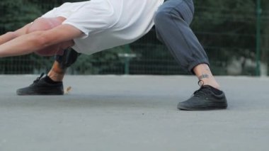 Sıra dışı görünüşlü genç erkek spor alanında esneme egzersizleri yapıyor, sporcu spor yapıyor..